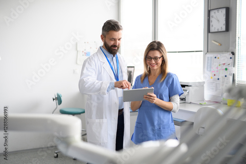 Doctor and female nurse looking at test results in tablet. Healthcare workers in Doctor's Office.