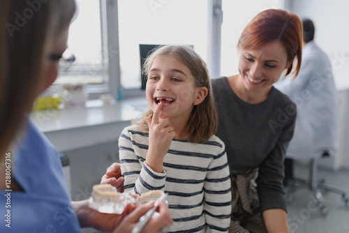 Canvas Print Girl showing her lost tooth to the dentist during a routine checkup at the dental clinic