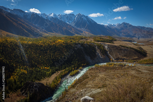 A stunning mountain river flows through a forest, surrounded by snowy peaks and valleys