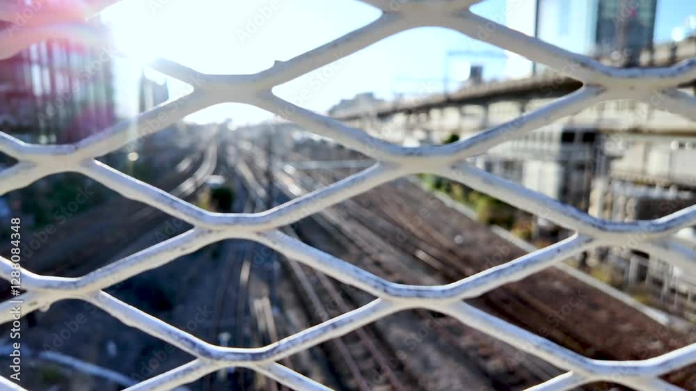 Sun shining through an expanded metal mesh fence with Osaka train lines in the background
