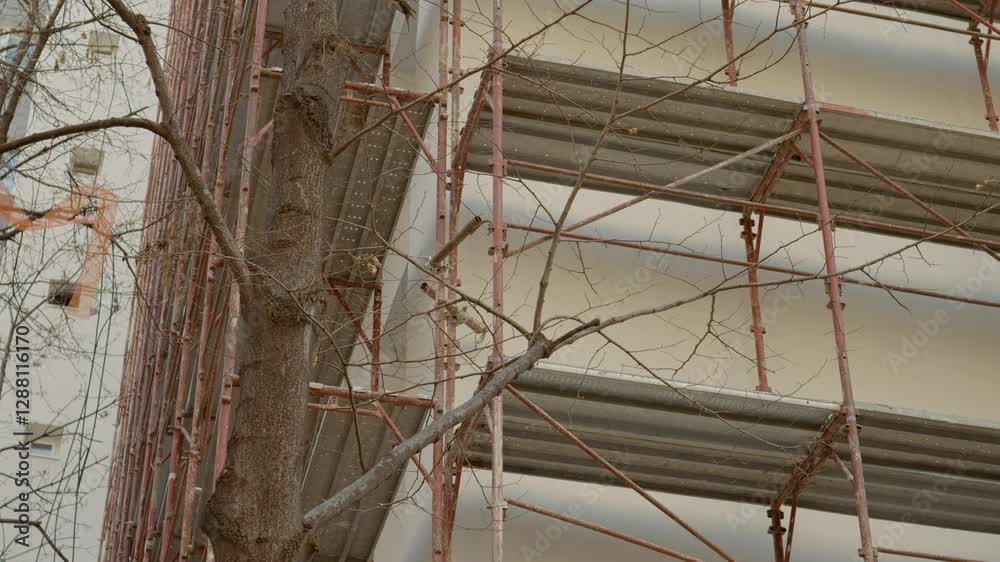An empty construction site showcases scaffolding for a block of flats. Workers prepare for insulation and rehabilitation efforts to enhance building efficiency and aesthetics.