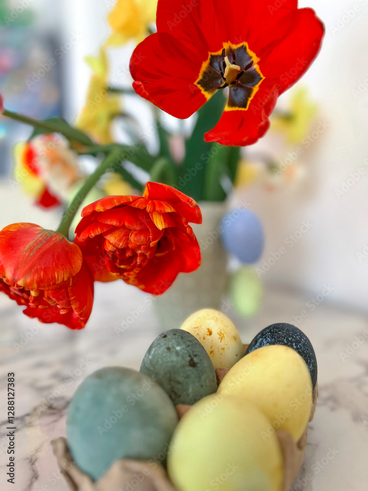 Bright colorful eggs are packed on the table next to a bouquet of tulips. An Easter card. Close. Vertical photography