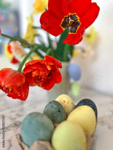 Bright colorful eggs are packed on the table next to a bouquet of tulips. An Easter card. Close. Vertical photography