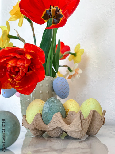 Obraz na płótnie Bright colorful eggs are packed on the table next to a bouquet of tulips. An Easter card. Close. Vertical photography w salonie