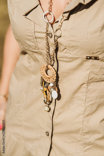 close up view of beautiful woman in dress holding necklace 