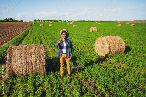 African farmer is standing in his agricultural field. He is cultivating clover and making bales of hay. photo