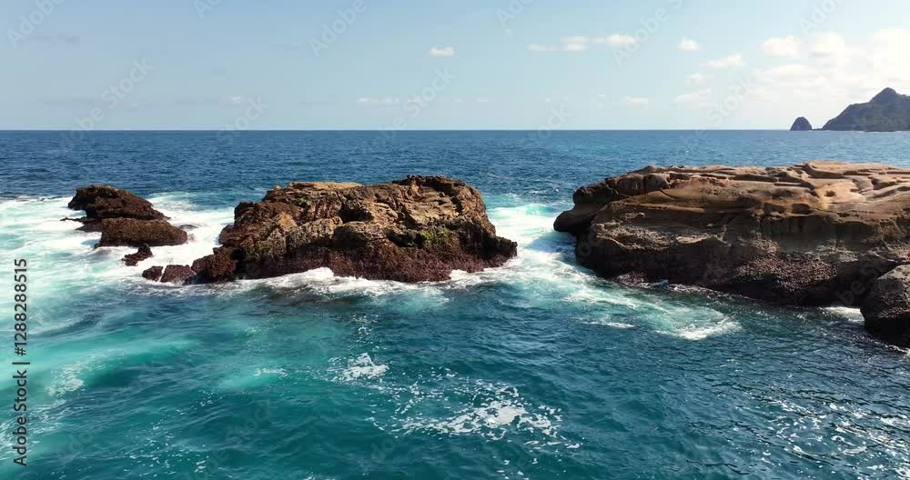 Aerial view & drone shot of a rock formation in the sea on which waves are breaking and white wave foam is forming / September 2024: South Lombok - Indonesia / 4K, UHD Aerial view & drone shot of a rock formation in the sea on which waves are breaking and white wave foam is forming / September 2024: South Lombok - Indonesia / 4K, UHD