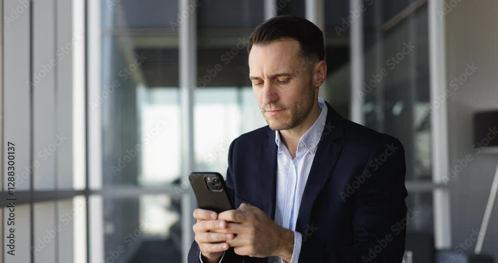 Focused serious Hispanic company director man in formal jacket using financial service on smartphone for online transactions, payment, typing on mobile phone, looking away, thinking