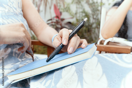 Close-up of woman's hand with pen on notepad listening to her interlocutor while sitting in chair. photo