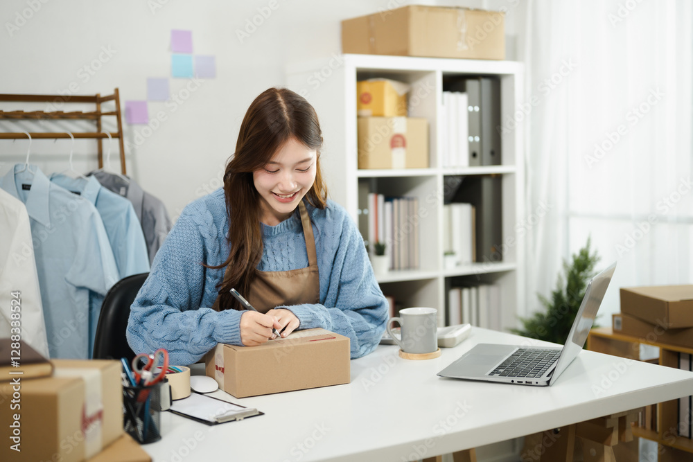 A small business owner in an apron prepares a parcel for shipping, labeling it with a pen, Order Fulfillment for Small Businesses A small business owner in an apron prepares a parcel for shipping, labeling it with a pen, Order Fulfillment for Small Businesses