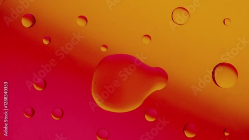 a large drop connects to a smaller drop on a red-yellow gradient background. High resolution 4k video.
