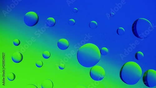 several drops join together on a blue-green gradient background. High resolution 4K video.