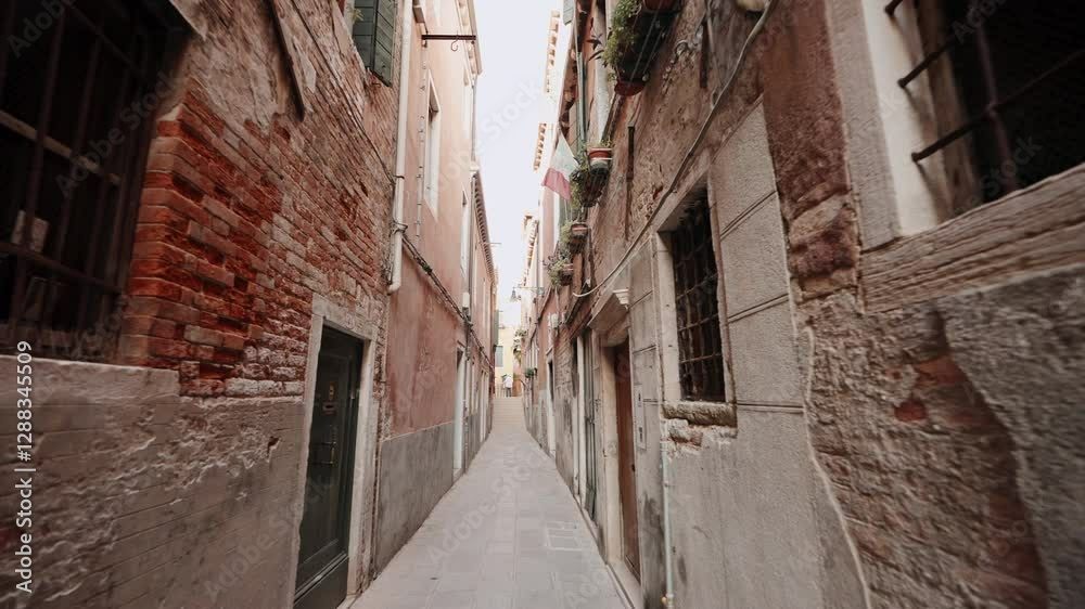 Classic Venetian alley with warm earth-toned walls, old iron window grates, and charming boutique. Sunlight creates inviting atmosphere as visitors experience culture heritage of Italy. Travel concept Classic Venetian alley with warm earth-toned walls, old iron window grates, and charming boutique. Sunlight creates inviting atmosphere as visitors experience culture heritage of Italy. Travel concept