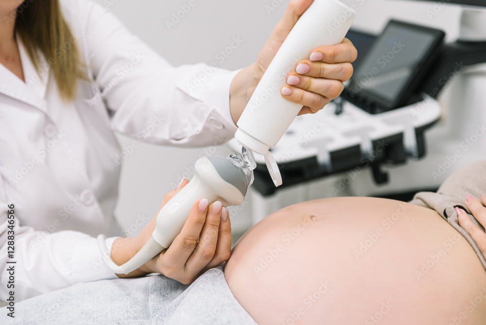 Obraz premium Gynecologist performing ultrasound scan on pregnant woman's belly