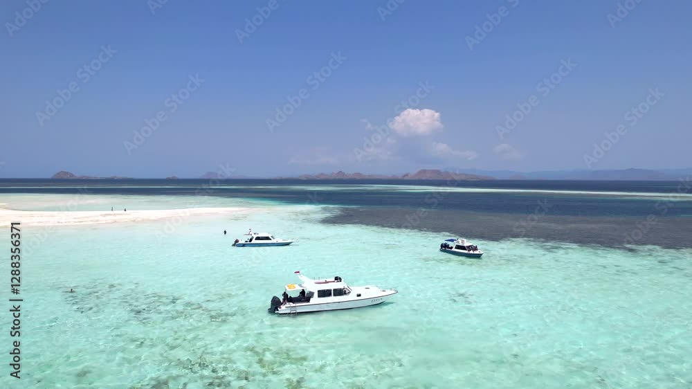 Aerial drone shot of turquoise waters with boats anchored in Komodo National Park, Indonesia. Scenic travel destination on a sunny summer day with a tropical vibe. Aerial drone shot of turquoise waters with boats anchored in Komodo National Park, Indonesia. Scenic travel destination on a sunny summer day with a tropical vibe.