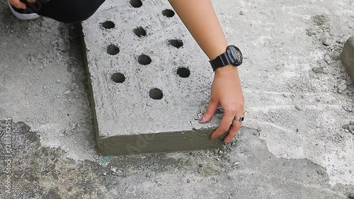 Indian woman inspecting imperfect perforated concrete slab, indicating the product is not meant for use.