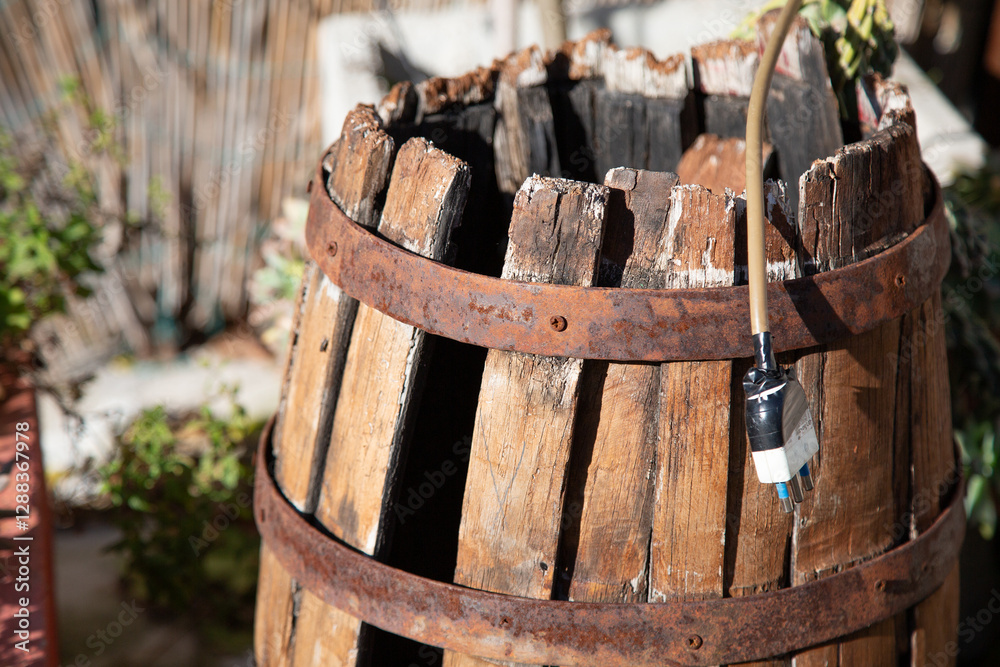A cylindrical wooden barrel with a hose securely attached to it A cylindrical wooden barrel with a hose securely attached to it
