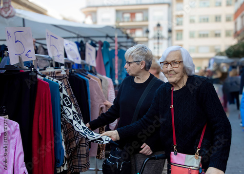 Two middle-aged women looking at clothes being sold at a flea market