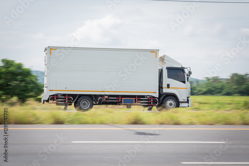 Motion blurred image, of a small white truck for logistics on the roads.