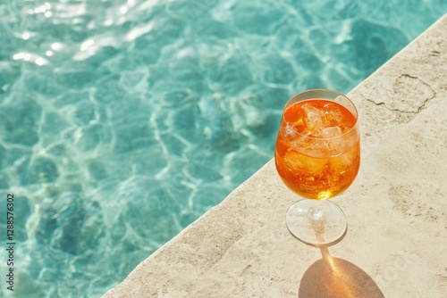 Aperol spritz cocktail in a glass on the edge of a swimming pool, with sunlight and shadow, close-up, top view, minimalistic, pastel colors