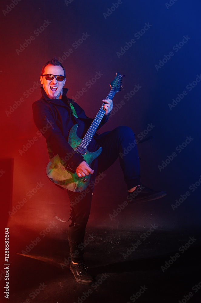 Fototapeta premium Musician rock passionately guitarist plays electric guitar against red and blue background