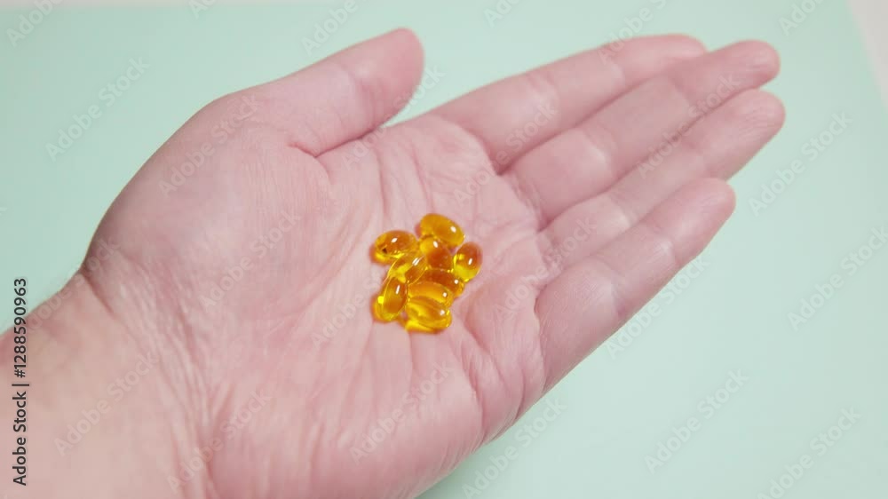 Omega 3 fish oil capsules pouring from a white plastic bottle onto an open hand on a light green background Omega 3 fish oil capsules pouring from a white plastic bottle onto an open hand on a light green background