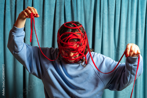 Woman in blue with her head tied with red threads against blue velvet curtains background . Mental problems concept.