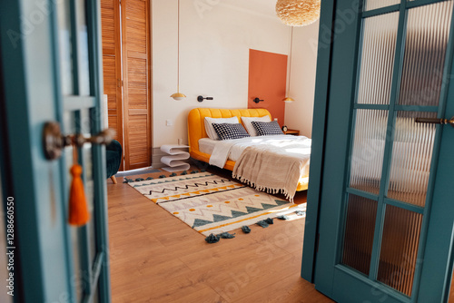 A cozy bedroom with white walls. An open stylish blue door. Wooden bed with stylish bedside tables and a soft fluffy carpet. Modern and comfortable interior.