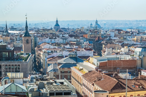 Panoramic view of Madrid historic center with a focus on traditional rooftops, churches, and iconic domes. This aerial image captures the essence of the city's architectural beauty from above
