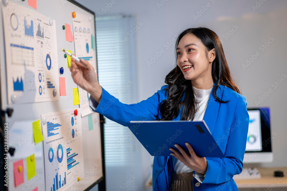 A woman in a blue suit is pointing at a whiteboard with a lot of graphs