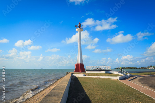 Lighthouse along waterfront in Belize City with clear blue sky and calm waters