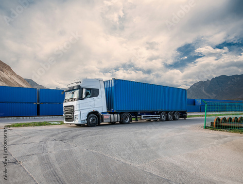 A large blue semi truck is parked in front of a sign that says 20