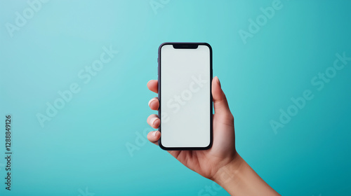 Hand holding a smartphone with blank screen against blue Background. Clean and minimalistic look. Mockup design. 