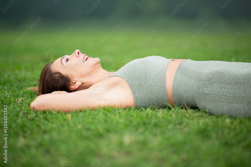Sports woman lying on back on green grass, smiling and embracing a moment of relaxation Sports woman lying on back on green grass, smiling and embracing a moment of relaxation