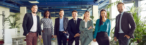 Group portrait of happy professional international business team standing together in row and smiling. Multiracial confident business people posing in corporate office, looking at camera. Banner.