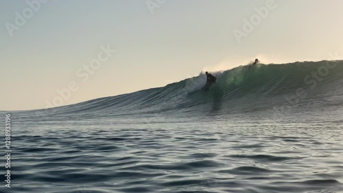 Male surfer rides an ocean wave at evening time and beautiful light.Wide angle slow motion video. Shooting from water