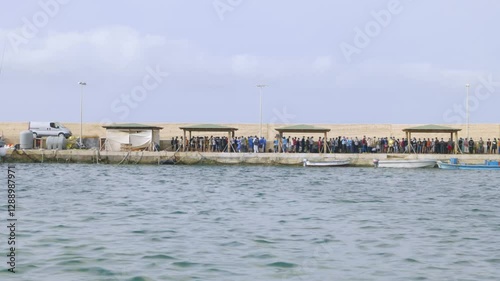 Lampedusa, Italy - June 29, 2021: Migrants arrive by boat on the Italian island of Lampedusa, seen standing on a pier after disembarking from a vessel