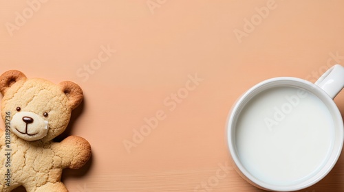 Sweet bear-shaped cookie next to warm cup of milk on soft backgr