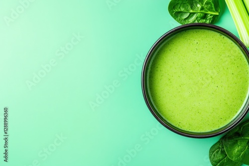 Bright green soup in bowl surrounded by fresh spinach and celery