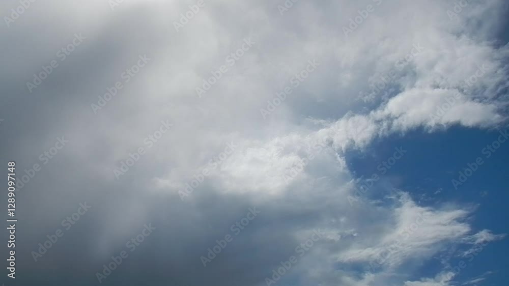 Blue sky, sun and slowly moving white and grey rainy clouds - natural sky background during weather change. Topics: cloudscape, sky space, meteorology, season, air space, season, climate Blue sky, sun and slowly moving white and grey rainy clouds - natural sky background during weather change. Topics: cloudscape, sky space, meteorology, season, air space, season, climate
