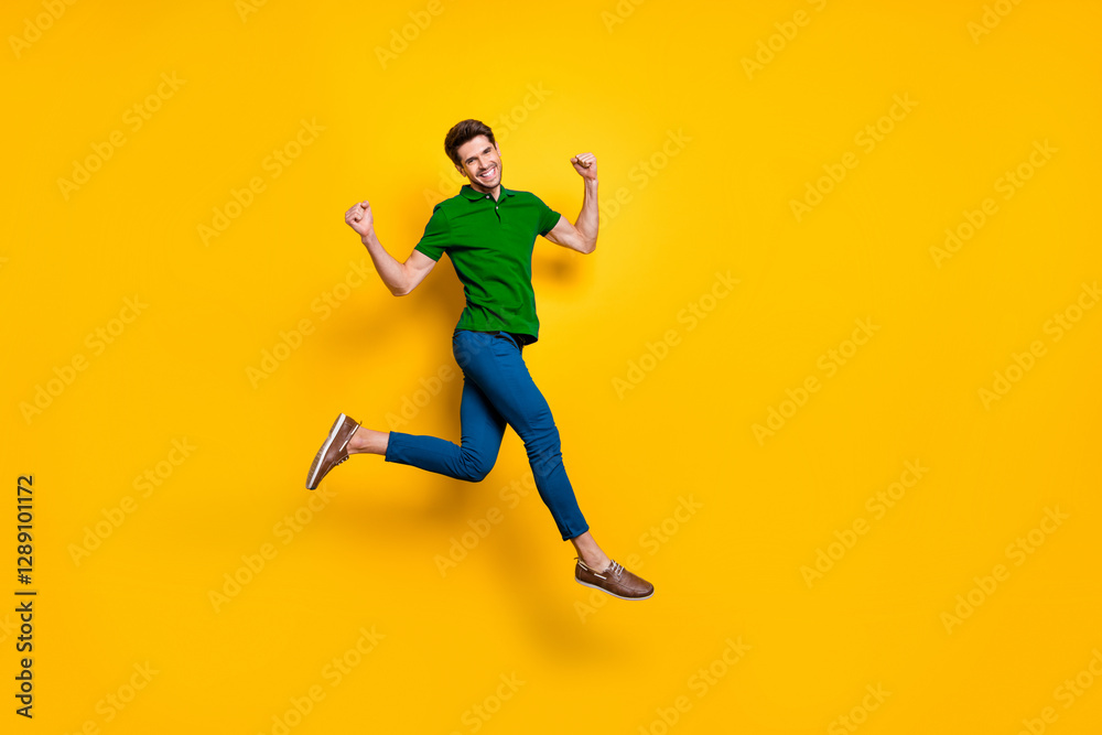 Full length body size photo of cheerful positive strong man running jumping demonstrating his powerful muscles wearing blue pants trousers purple t-shirt isolated over vivid color background Full length body size photo of cheerful positive strong man running jumping demonstrating his powerful muscles wearing blue pants trousers purple t-shirt isolated over vivid color background