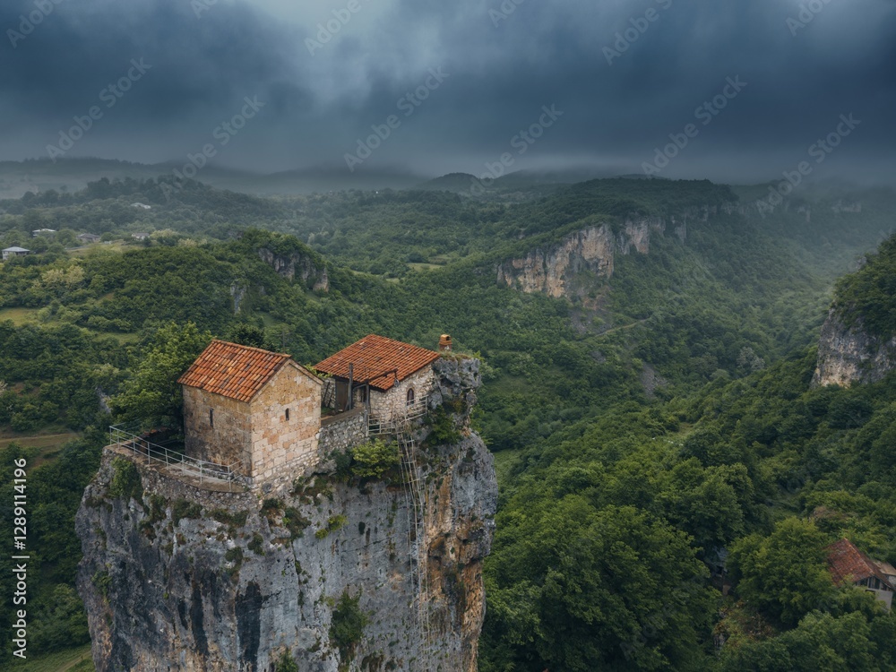 Fototapeta premium forest covered gorge and house on a rock pillar, cliff house on top, aerial view