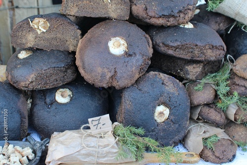 Rustic, handmade dark bread loaves with garlic baked inside, displayed at a market stall. A traditional, hearty, and flavorful artisanal bread