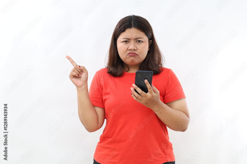 Skeptical asian modern girl, holding smartphone, pointing finger left at empty space and frowing hesitant, has doubts. Isolated on white background Skeptical asian modern girl, holding smartphone, pointing finger left at empty space and frowing hesitant, has doubts. Isolated on white background