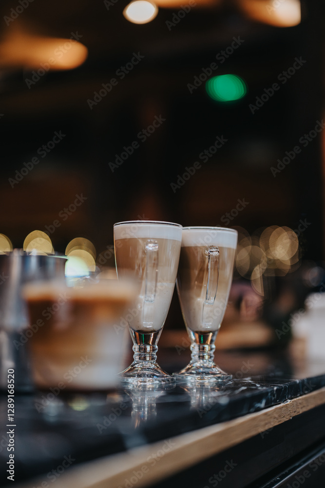 A beautifully captured scene featuring coffee drinks in stylish glass mugs on a dark table, with warm bokeh effects in the background creating a cozy cafe atmosphere. A beautifully captured scene featuring coffee drinks in stylish glass mugs on a dark table, with warm bokeh effects in the background creating a cozy cafe atmosphere.