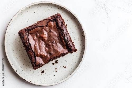 A rich, fudgy brownie sits on a simple plate, showcasing a perfect crackled surface and a luscious interior, inviting indulgence. photo