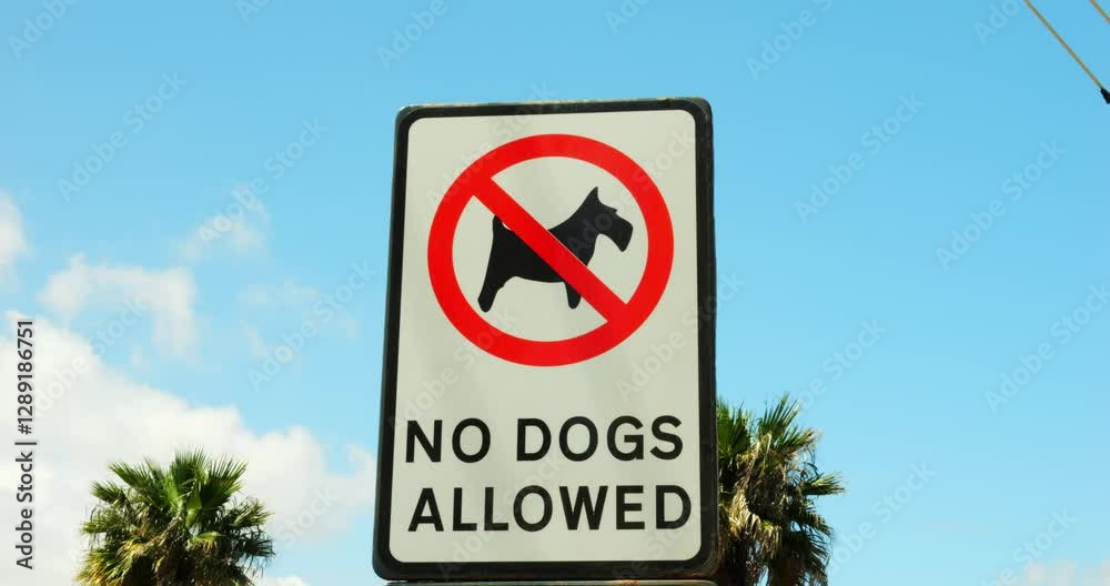 Steel plate with No Dogs Allowed caution under struck through canine in circle. Aluminum noticeboard prohibiting pet entrance against clear blue sky Steel plate with No Dogs Allowed caution under struck through canine in circle. Aluminum noticeboard prohibiting pet entrance against clear blue sky