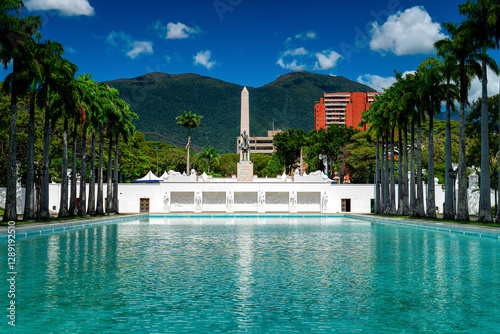 Panoramic view of Paseo Los Proceres in Caracas, Venezuela. Monument, turquoise water, mountains in the background.
