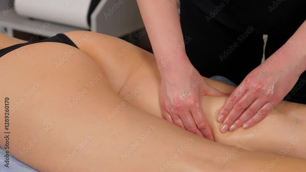 Hands of experienced masseuse giving buttocks and thighs massage to woman client to improve blood circulation and lymphatic drainage in spa salon. Body care procedure in beauty clinic