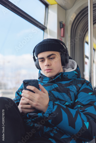 Teenager in public transport wearing headphones, focused on smartphone. Urban commuting, digital lifestyle, and modern youth culture. Concept of online learning, social media, daily routine. Copyspace
